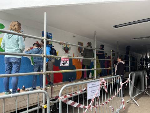 Children and adults standing on scaffolding painting at the Meldreth Wonderpass