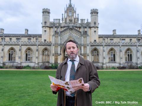 Photograph of David Mitchell in character as Ludwig standing in the grounds of Kings College Cambridge