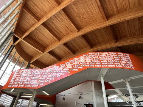 A photograph of one of the staircases at Cambridge South Station featuring an artwork titled "Together We" by the Turner Prize-nominated artist Mark Titchner.