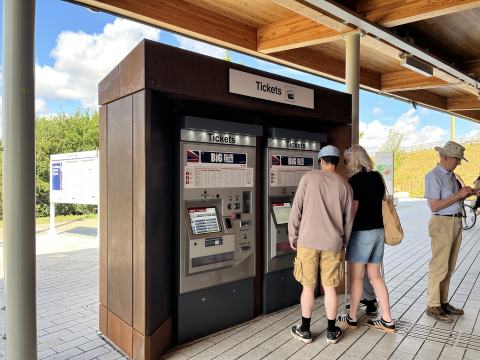 A photograph of 3 people using the ticket machine at Cambridge South Station.